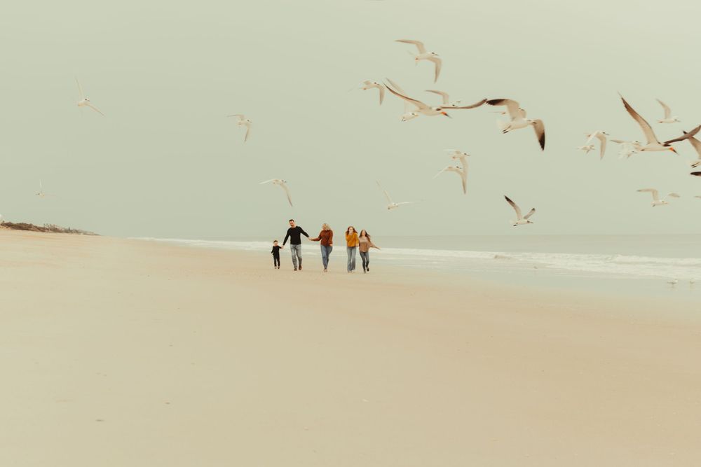 People walking along a serene beach shoreline at sunset.