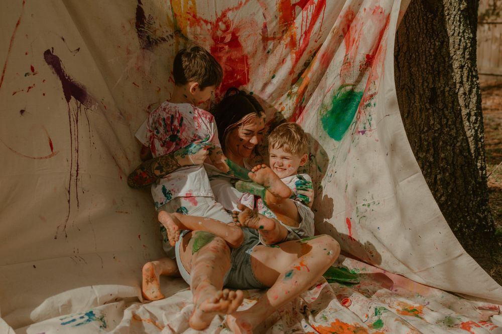 Artistic paint splatter photography session against white backdrop outdoors.