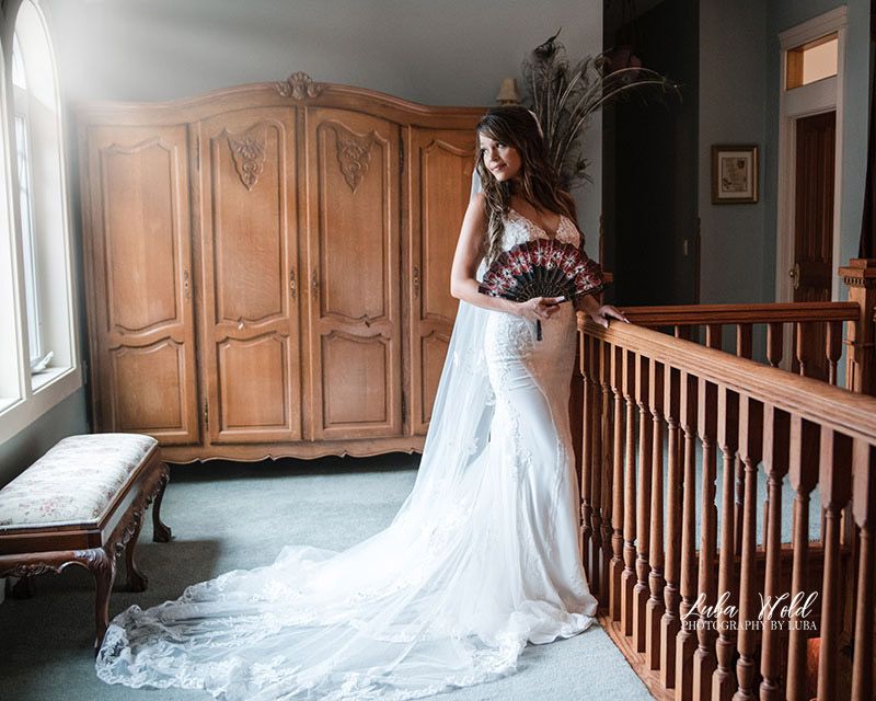 portrait of a bride by window light holding a fan from a wedding at Foxwood House by Spokane photographer Luba Wold
