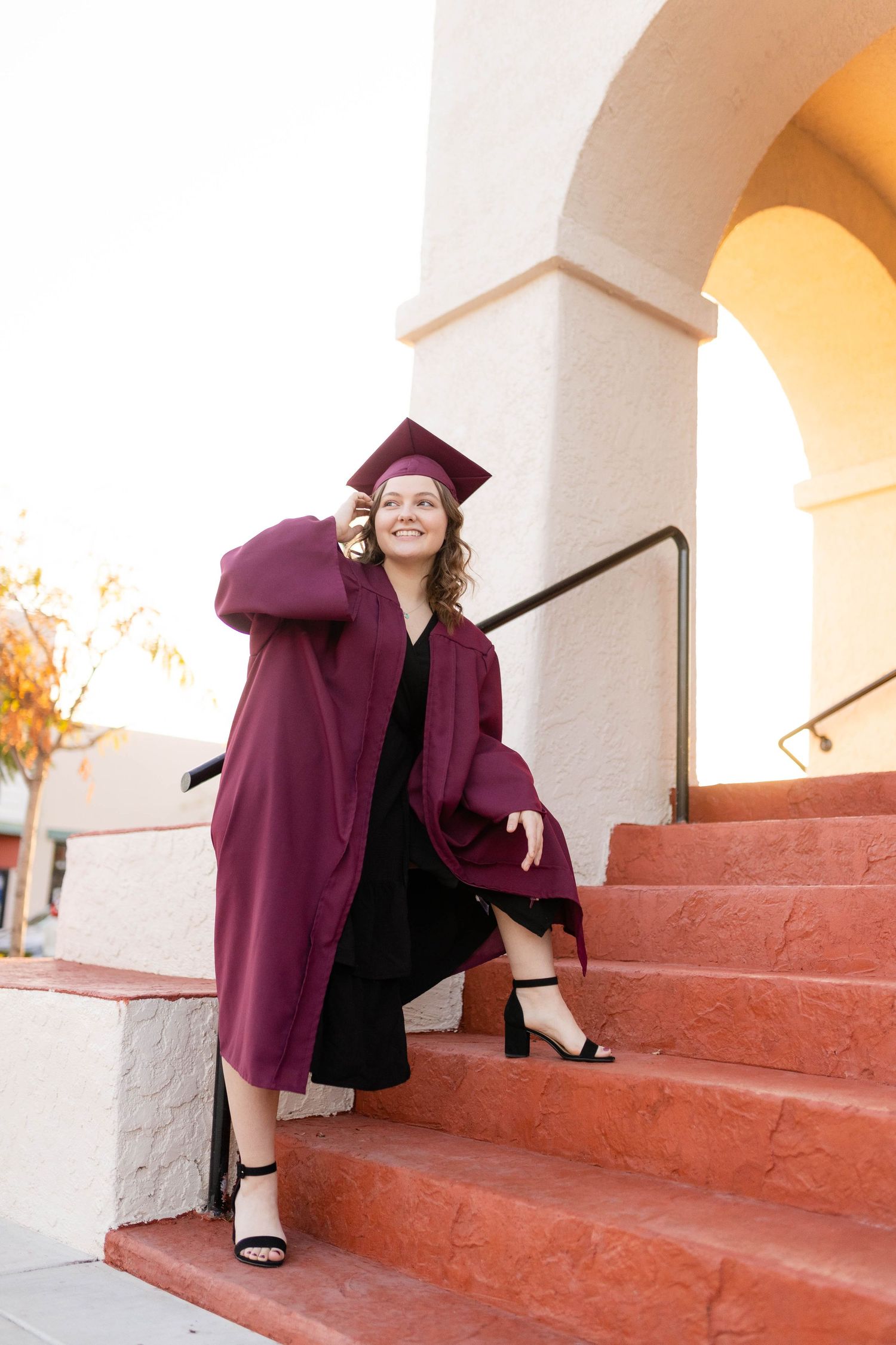 sassy pose on steps of girl in red grad cap in downtown Upland