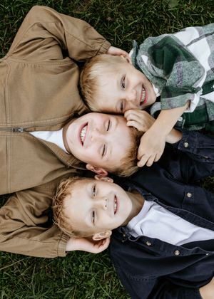 A series of candid outdoor portraits showing joyful expressions while lying on green grass.