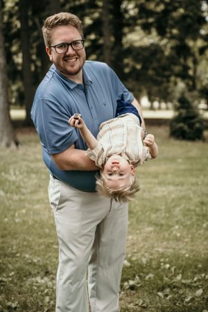 A playful moment captured outdoors of joyful parent-child interaction in a park setting.