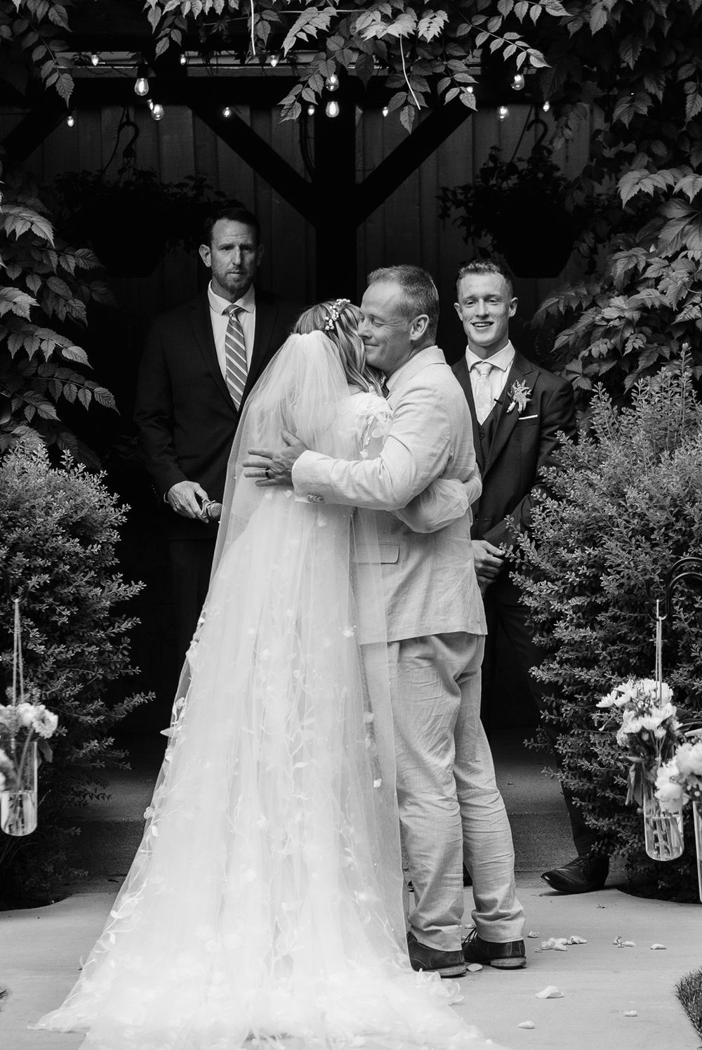 utah county Wedding celebration in black and white showing couple embracing under covered venue.