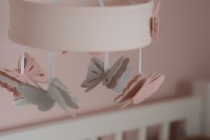 Pink and gray paper butterflies hanging from a white nursery lamp shade.