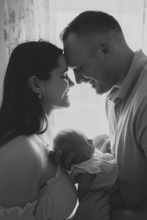 A series of intimate black and white photos showing tender moments between parents and their newborn baby.