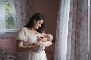 A quiet moment by the window in a pink-toned nursery setting.