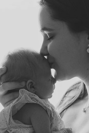 Tender black and white portrait showing a gentle moment between parent and baby.