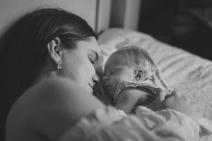Black and white photo series showing quiet moments between parents and their newborn baby in bed.