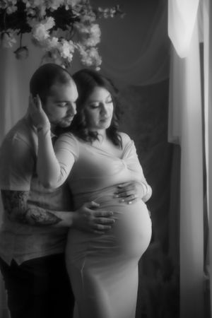 A black and white intimate maternity portrait of a couple sharing a tender moment.