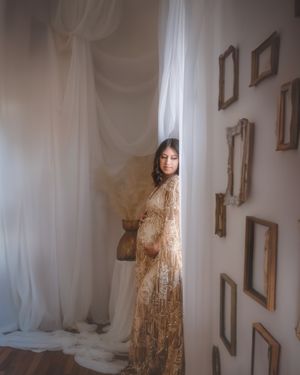 Artistic maternity photo with woman in lace dress posed beside vintage frames in the Hudson Valley,NY.