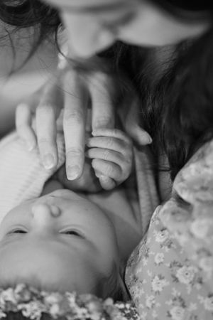 A tender black and white close-up moment of a baby being gently touched by caring hands in the Hudson Valley,NY.
