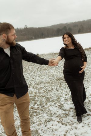 A couple dances together in a snowy field during a winter engagement photo session.