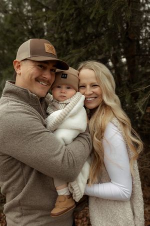 A family shares tender moments together outdoors in autumn wearing coordinating brown and white outfits.