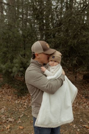 A tender outdoor moment captured in a series of photos showing a parent embracing a small child in a white blanket.