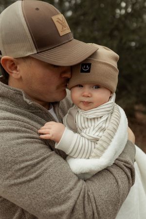 A series of tender moments between parent and child wearing matching beige caps and neutral toned clothing.