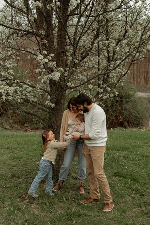 A family shares tender moments under blooming cherry trees in a springtime outdoor photo series.