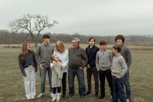 A group of people standing together in a field on an overcast day wearing casual clothing.