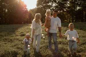 A family walks together through a sunlit meadow during golden hour, creating a warm and joyful outdoor scene.