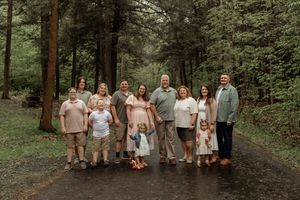 Wedding party in neutral colors walks together along a wooded forest path during an outdoor celebration.