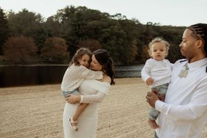 A family wearing white outfits shares tender moments together in a golden field during sunset.