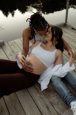Romantic couple sharing intimate moments on a wooden deck in casual white tops and jeans.
