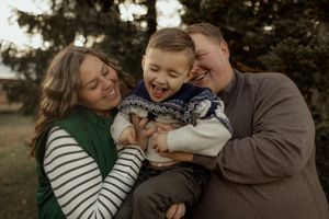 A family shares joyful moments together outdoors during a casual photo session in natural lighting.