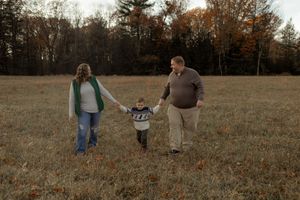 Family walking together through a rustic autumn field during golden hour.