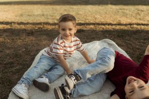 Family lying on grass in park during golden hour autumn photoshoot wearing coordinated outfits.