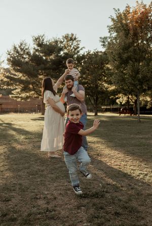 A family plays together in a grassy field at sunset, creating a series of joyful candid moments.