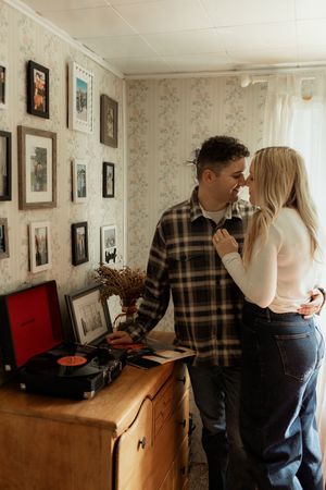 A sequence of four photos showing a couple in a living room with framed pictures on floral wallpaper.