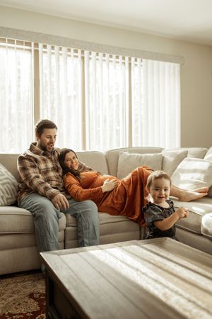 Four sequential photos show people relaxing on a couch in sunlit room with vertical blinds casting dramatic shadows.