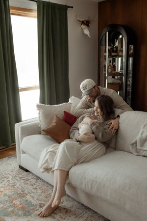 A sequence of cozy moments on a white couch with green curtains in the background showing relaxed indoor intimacy.