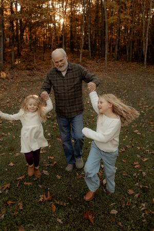 A sequence of four photos showing playful dancing in autumn leaves on a wooded lawn at sunset.