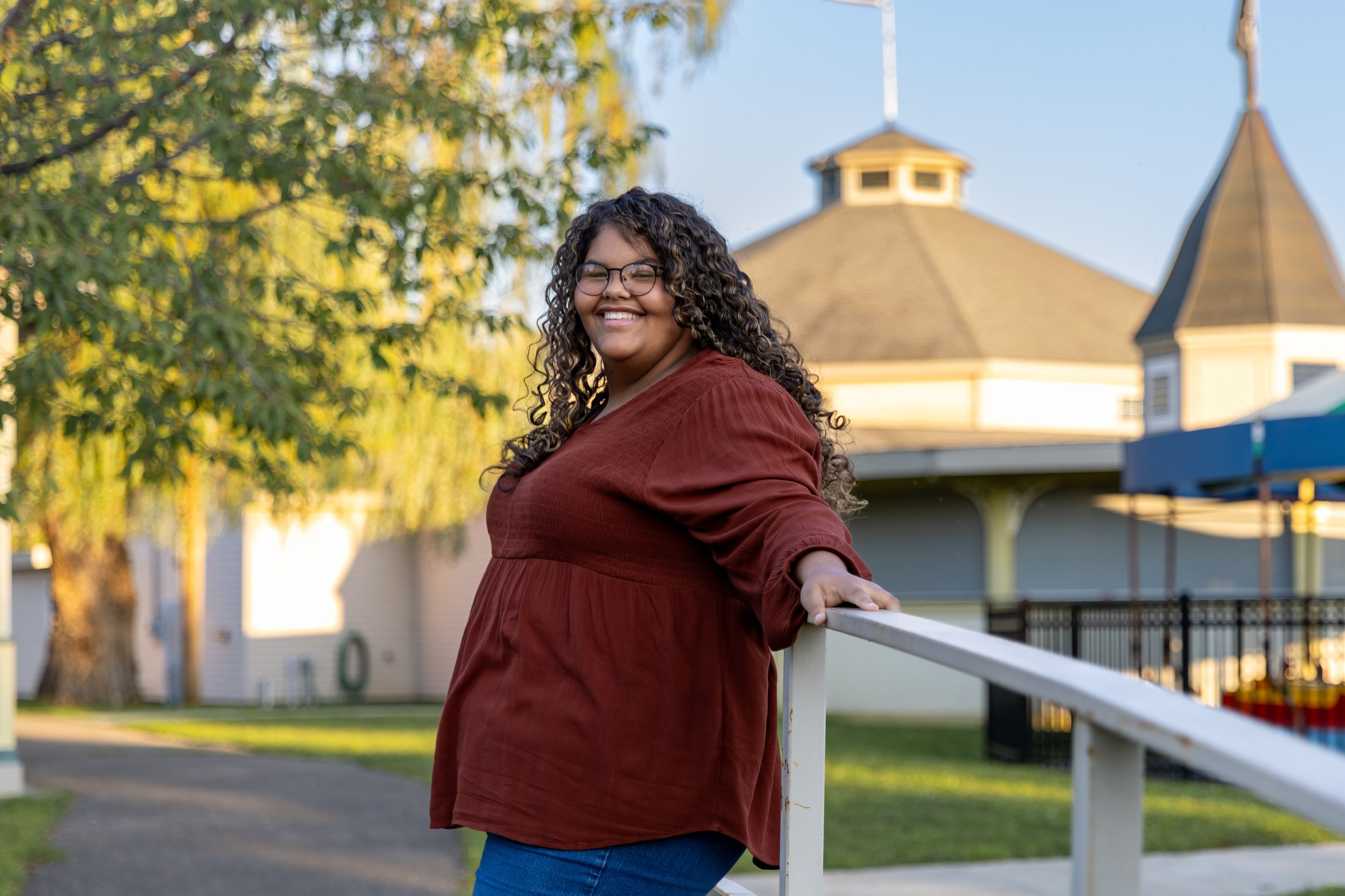 A casual portrait at a park with playground equipment and buildings in the background.