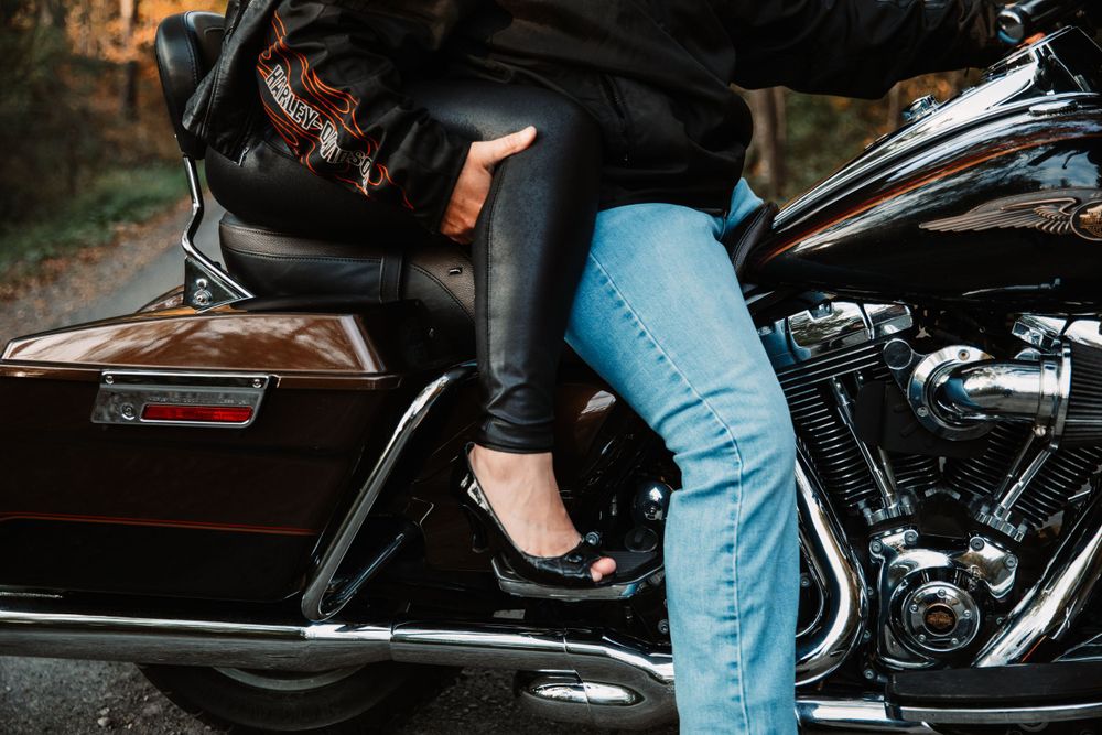 Close up of legs in jeans and boots straddling a motorcycle showing contrasting textures.