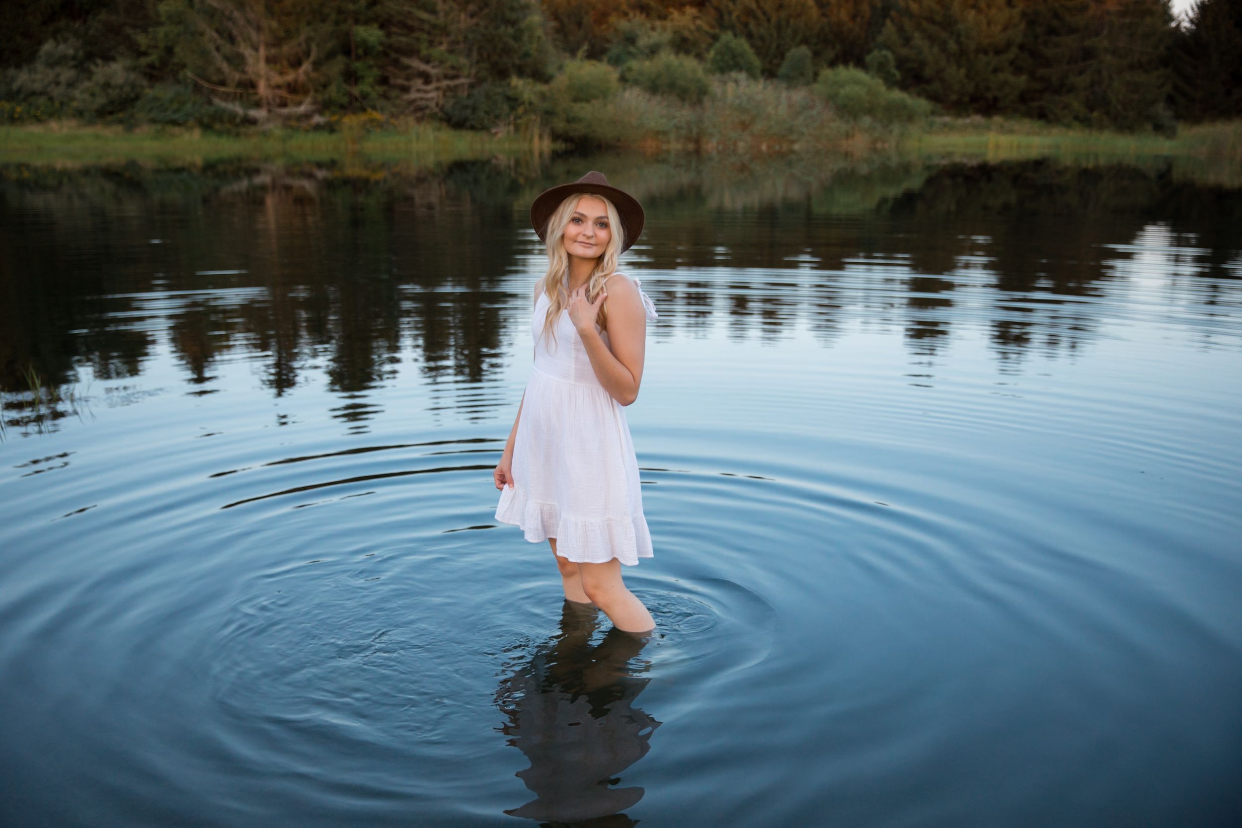 A dreamy portrait of someone standing in rippling water wearing a flowing white dress.