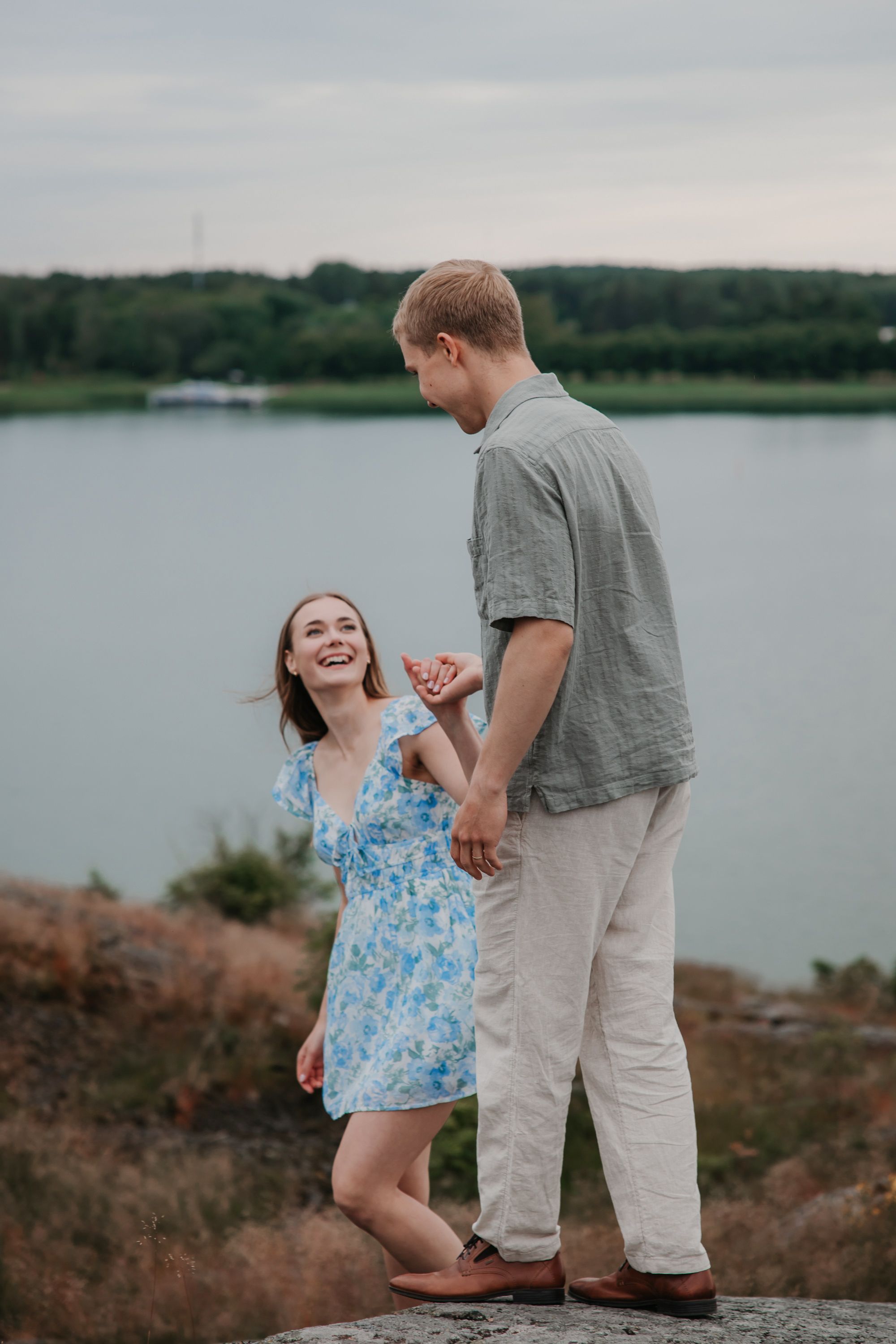 A couple sharing a playful moment together on rocky coastal terrain.