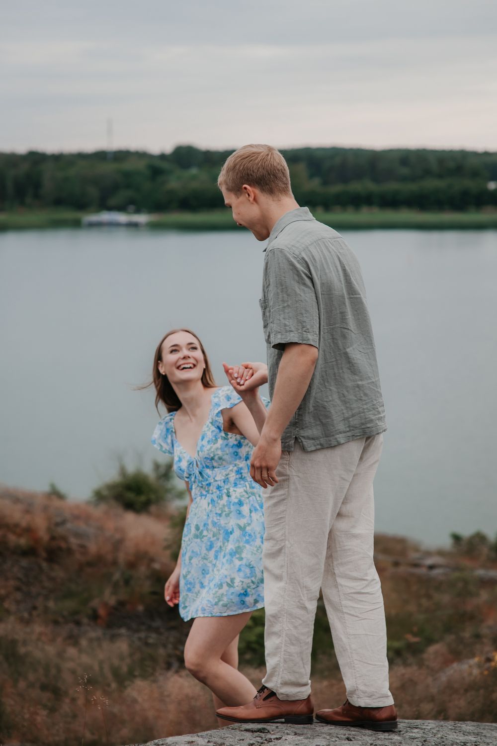 A couple sharing a playful moment together on rocky coastal terrain.