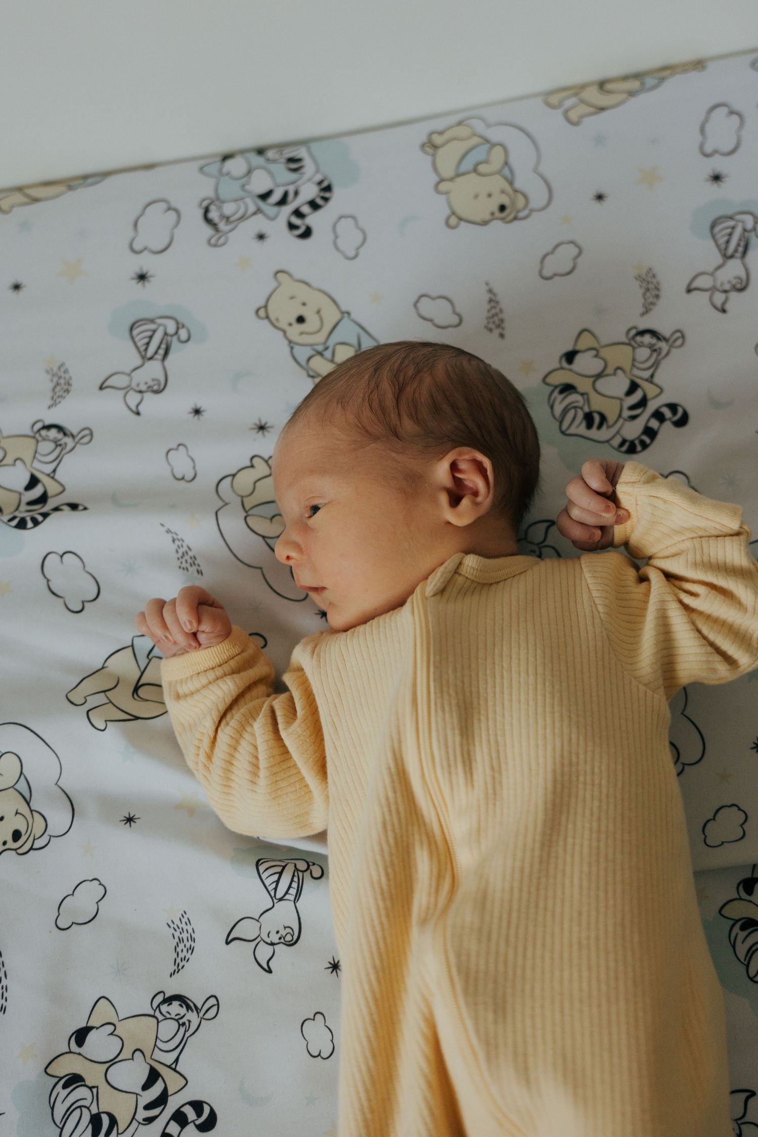 Newborn wrapped in white blanket sleeping peacefully in woven basket.