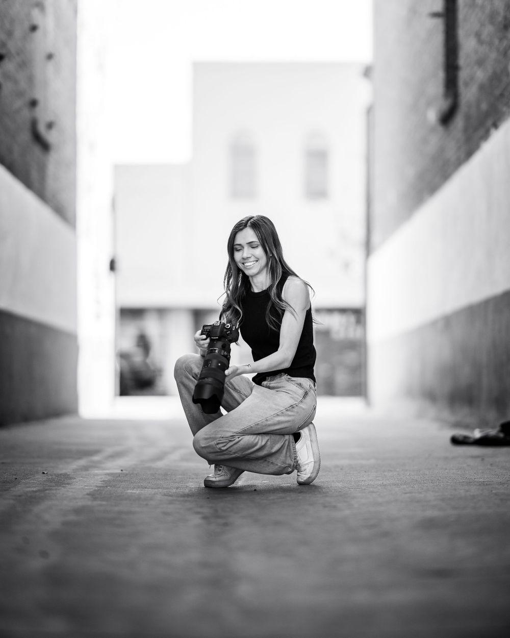 Photographer Sierra smiles while leaning on a railing in natural light, captured by Chris Cornish Photography.