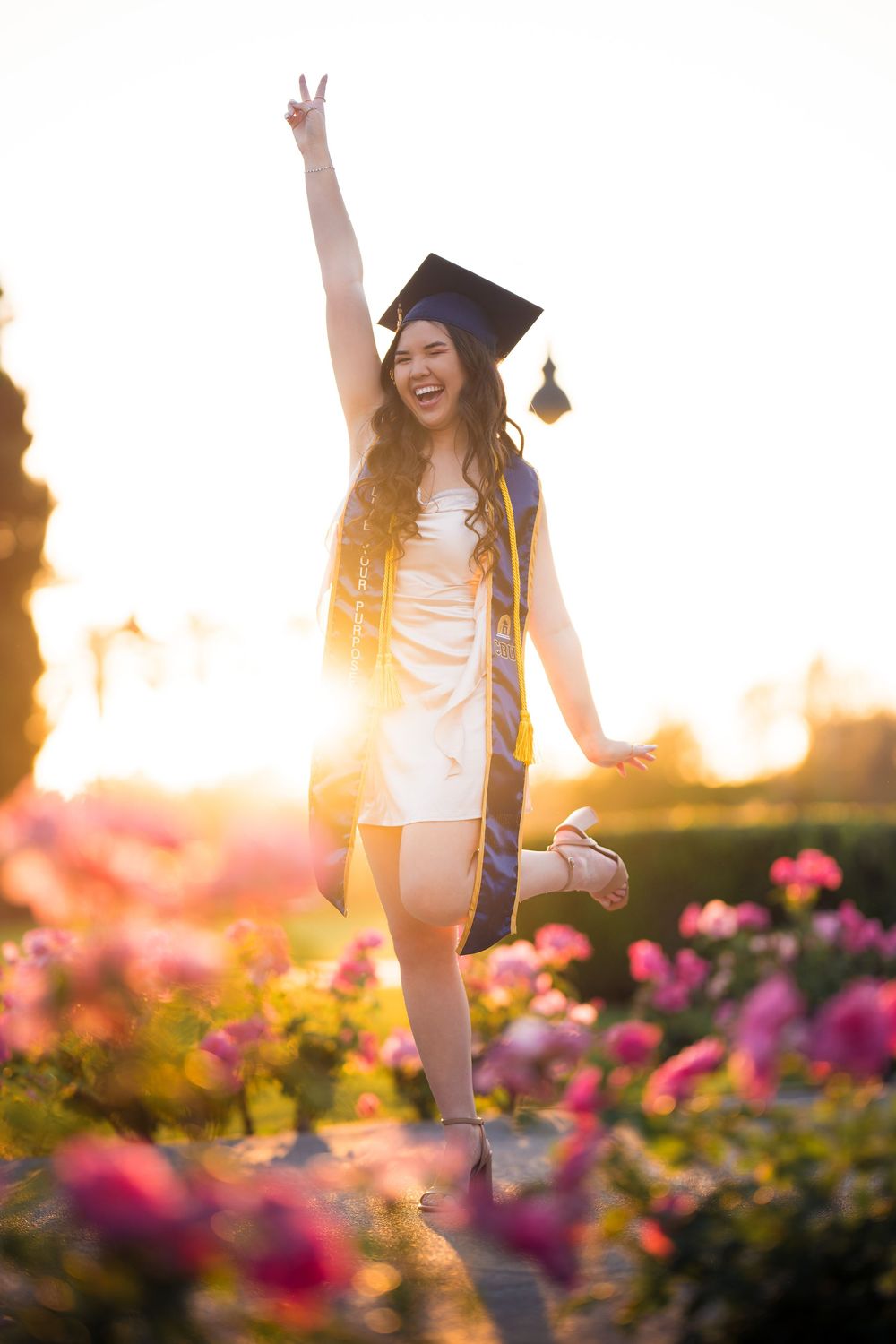 CBU graduate Shelby smiles in cap and gown while holding her diploma on campus, captured by Chris Cornish Photography.