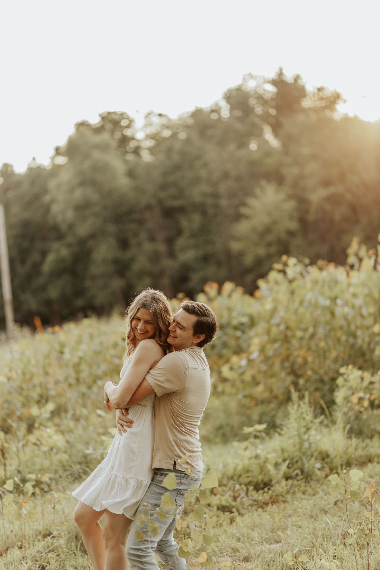 Romantic outdoor engagement photo in a golden wildflower field at sunset.