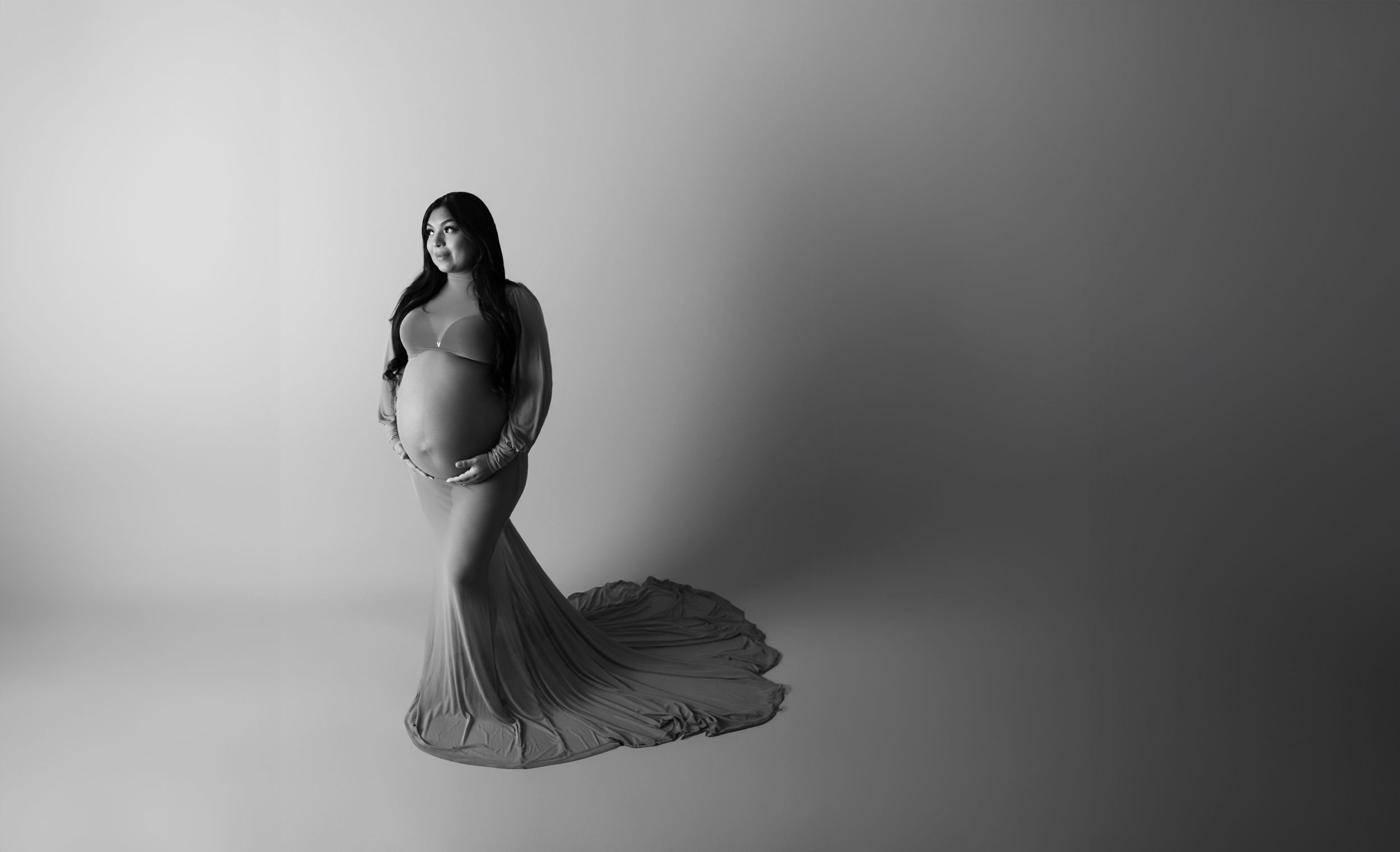 pregnant woman in a long dress, black and white image, simple paper backdrop, timeless and beautiful