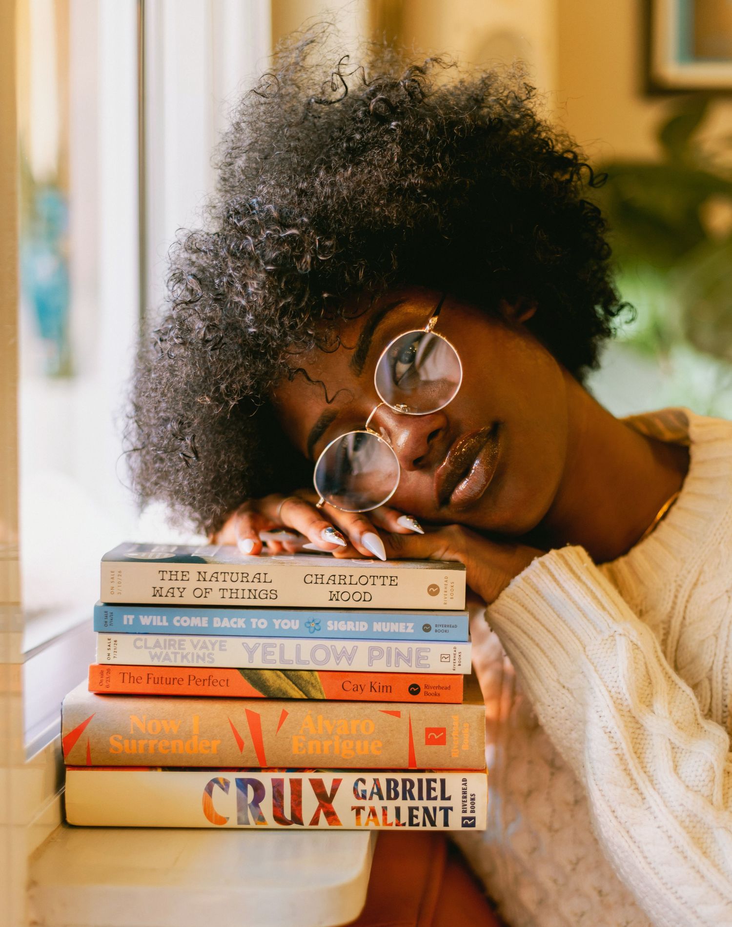 Stack of contemporary books with round glasses resting on top in warm lighting.
