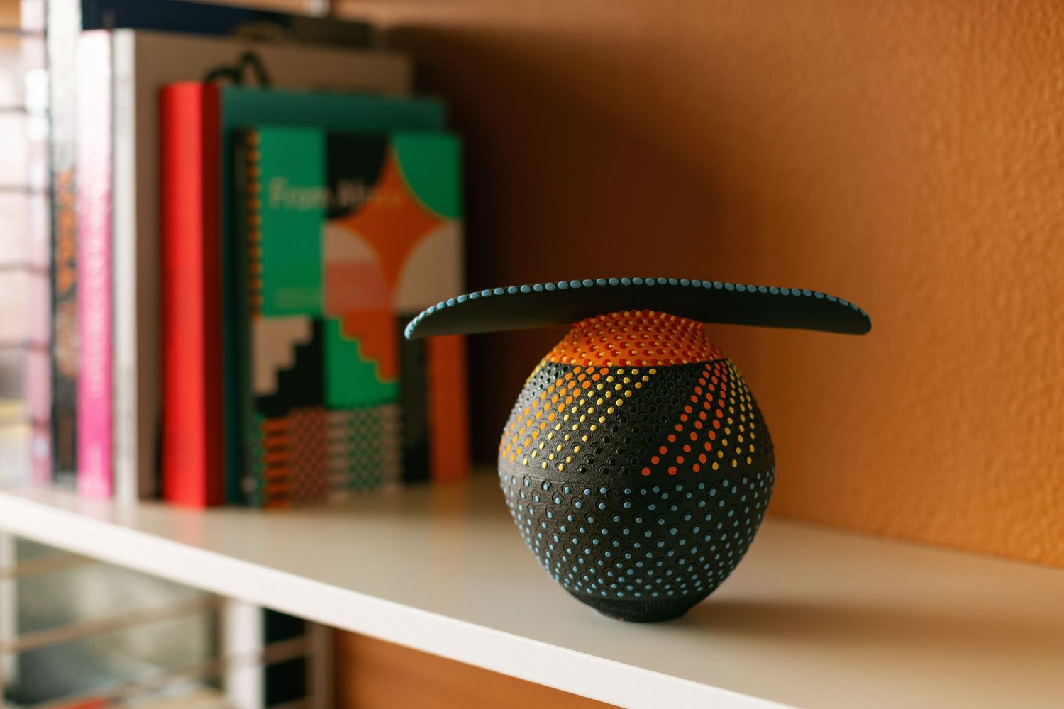 Decorative pottery vessels displayed on orange-tinted shelf.