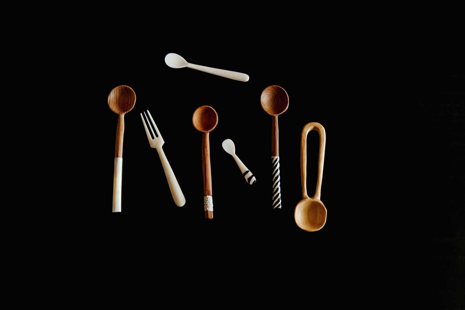 Minimalist arrangement of wooden utensils on black background.