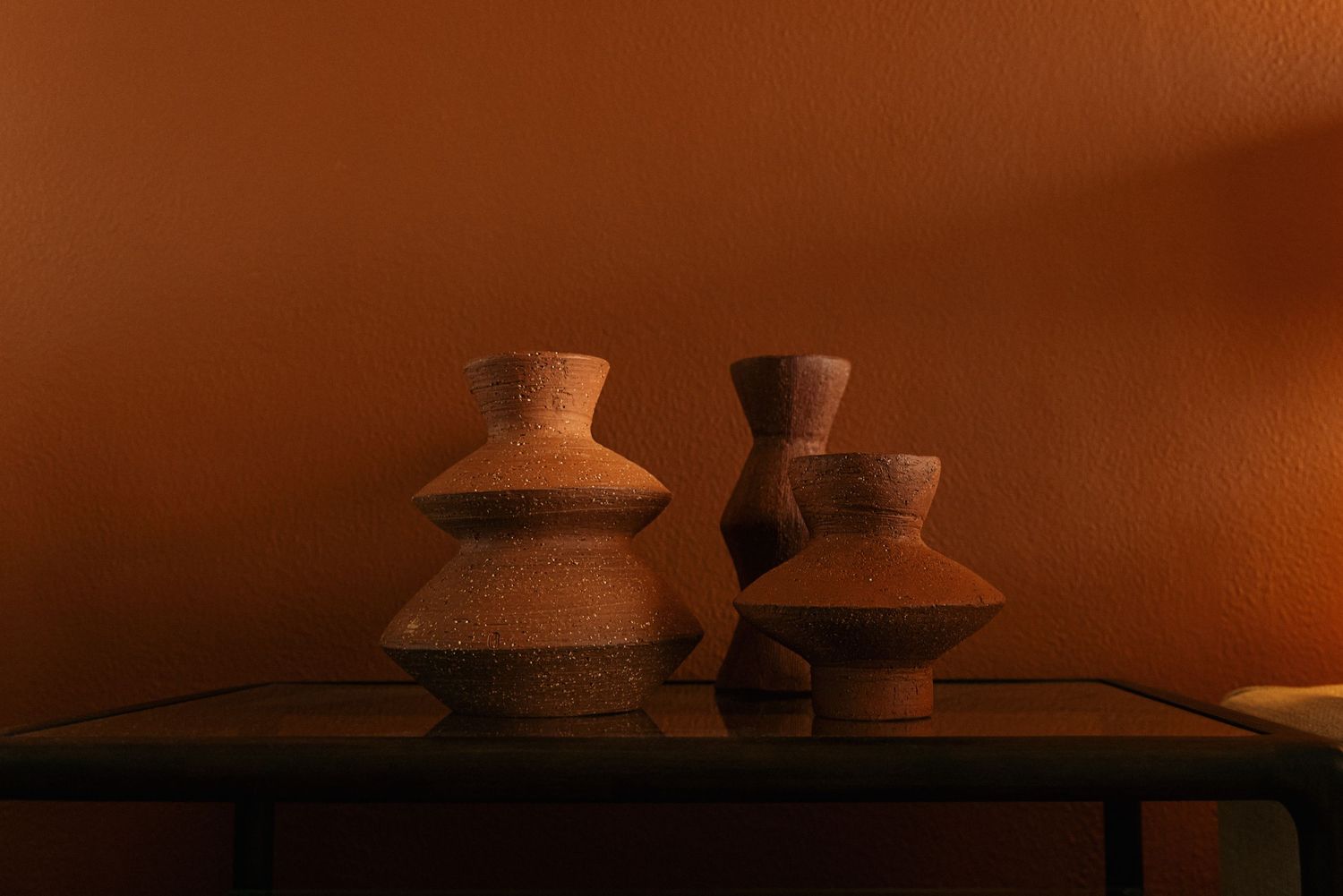 Warm-toned still life of ceramic pottery on shelf.