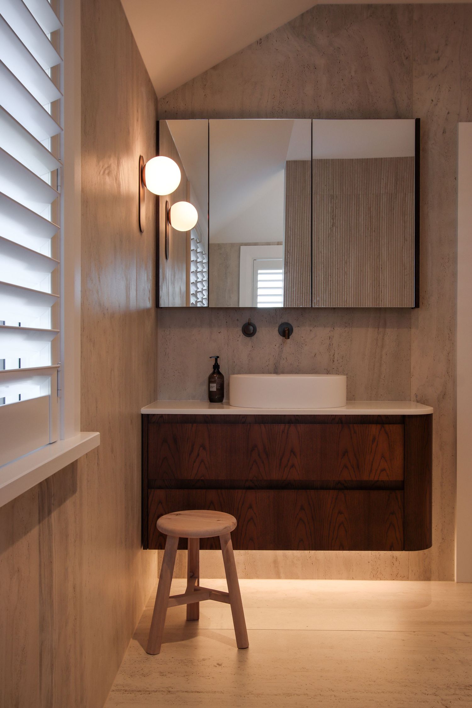 Modern minimalist bathroom interior with wooden elements and ambient lighting.