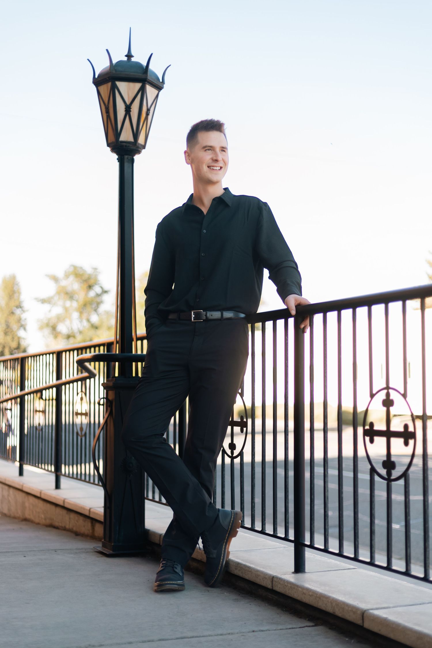 Casual portrait by decorative lamp post on outdoor deck railing.