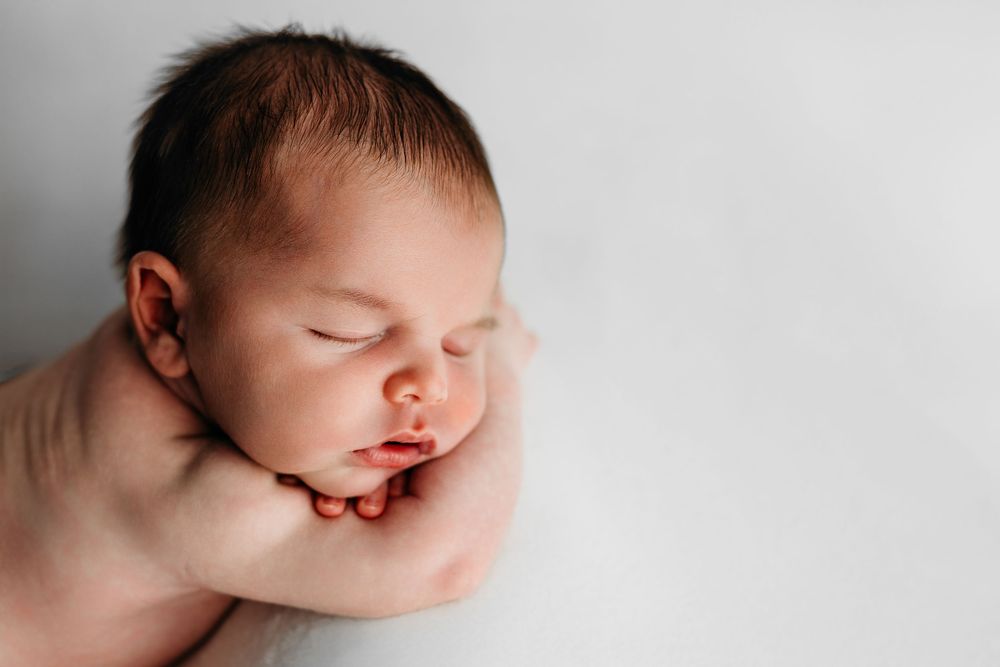 Black and white close-up of a sleeping baby on a soft white blanket in peaceful repose.